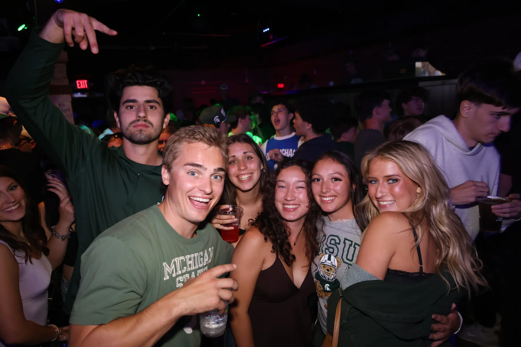Group of friends posing together in a crowded bar