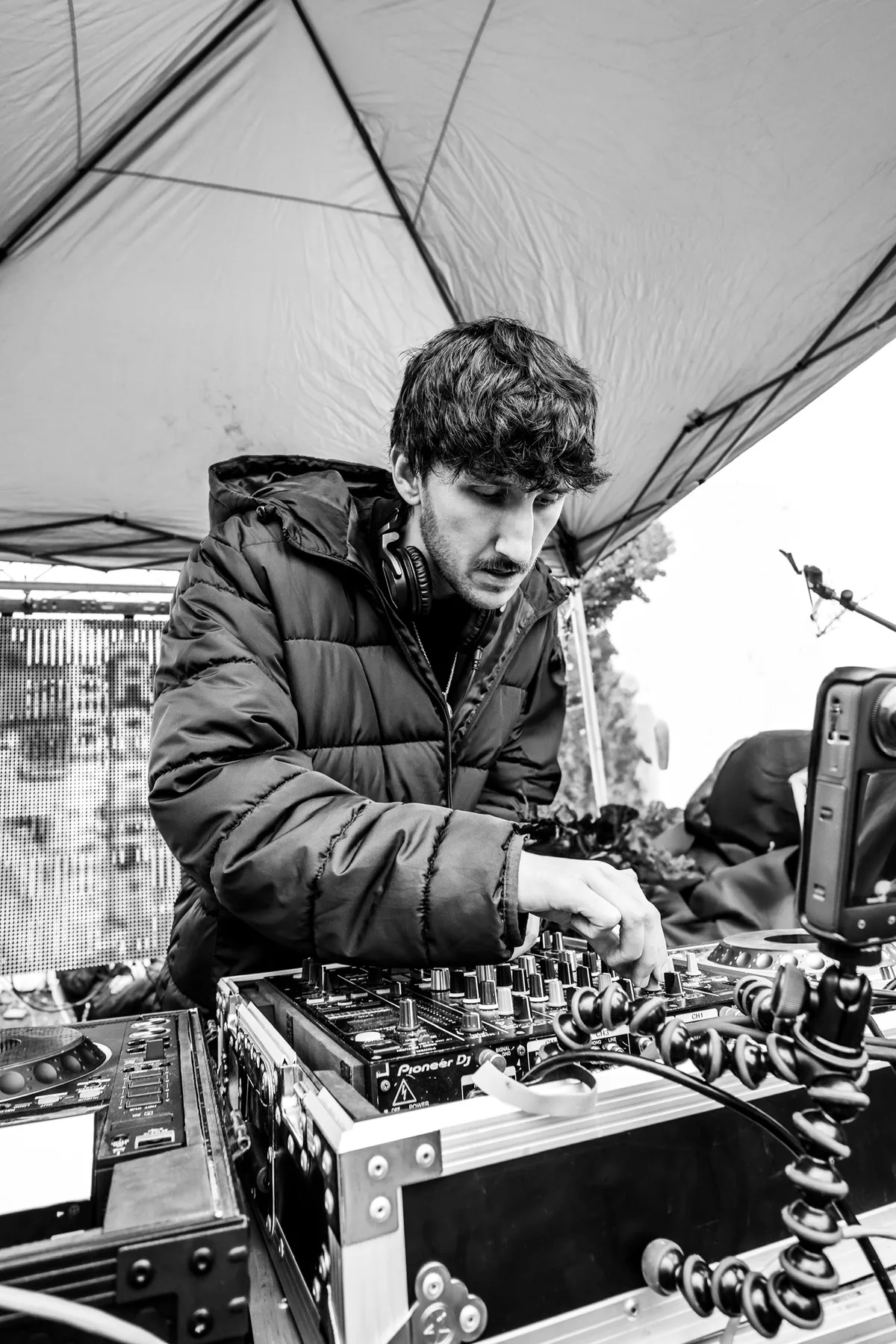 Black and white portrait of a DJ adjusting the mixer at an outdoor set