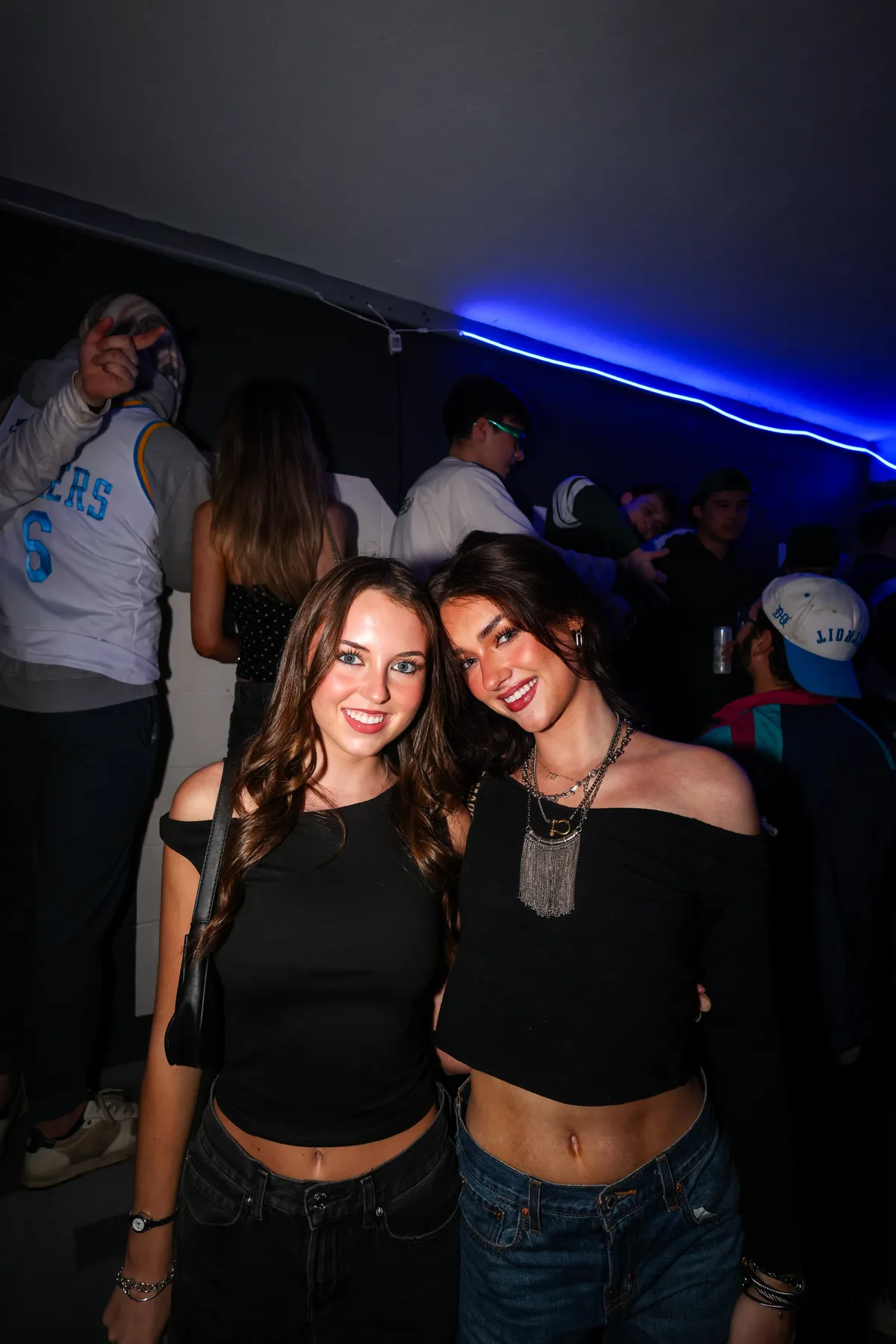 Two friends posing together under blue neon lighting