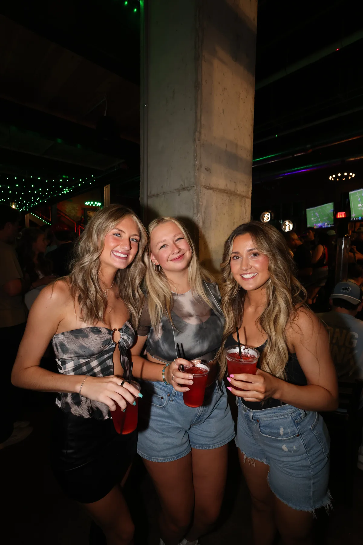 Three friends posing with drinks in hand