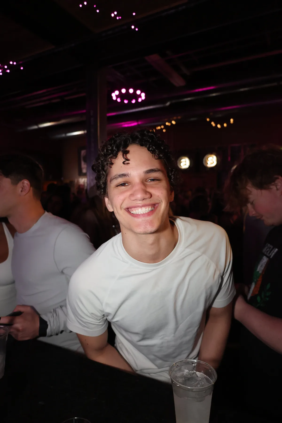 Guy smiling at the bar under string lights